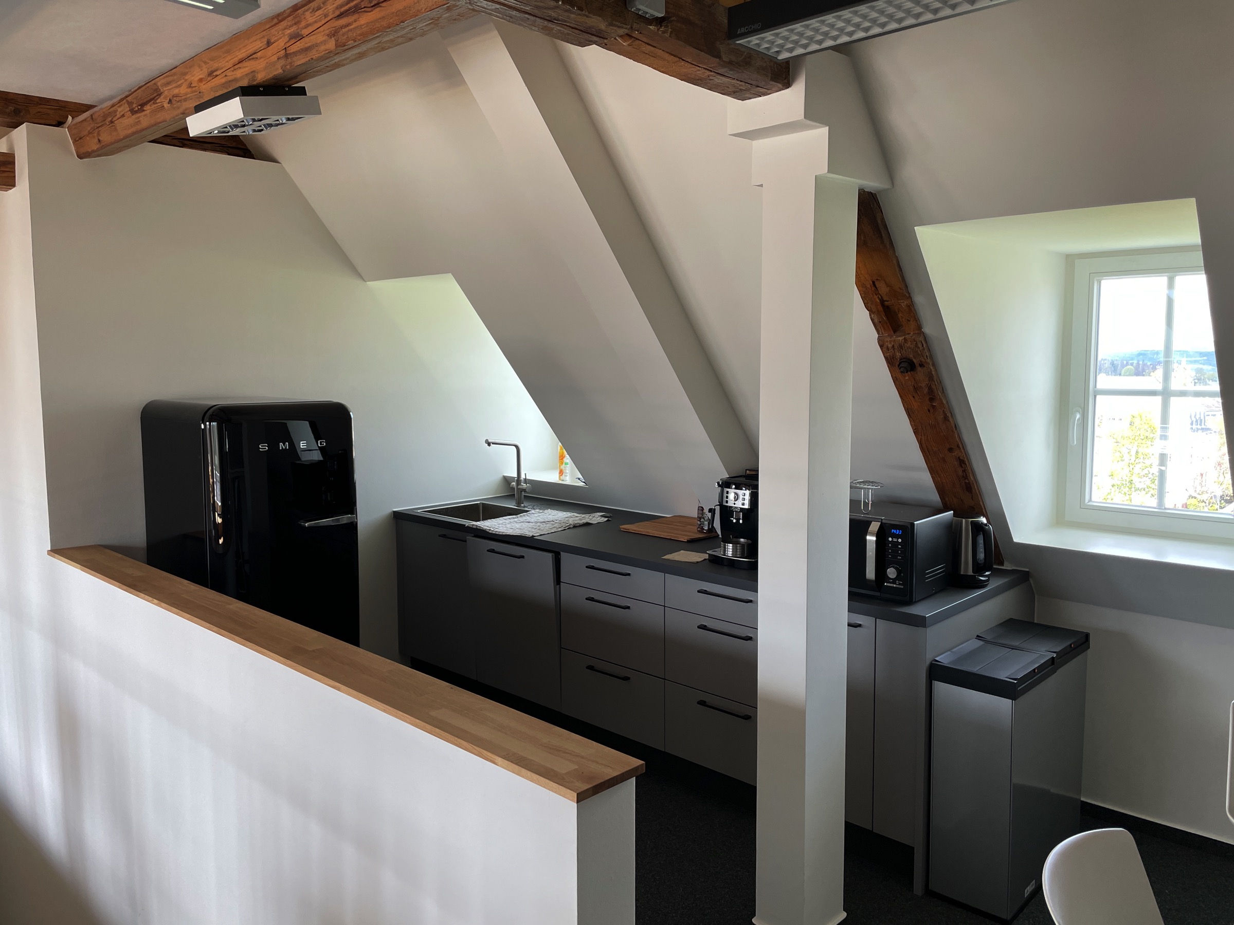 Kleine Küche mit Kaffeemaschine, Wasserkocher, Kühlschrank und Mikrowelle im Coworking Space.